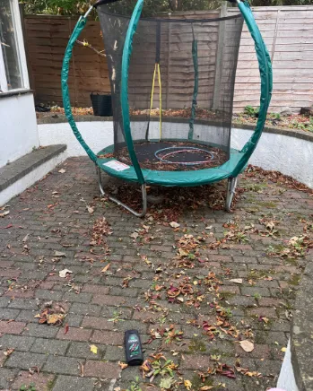 Brick patio and trampoline covered in fallen leaves