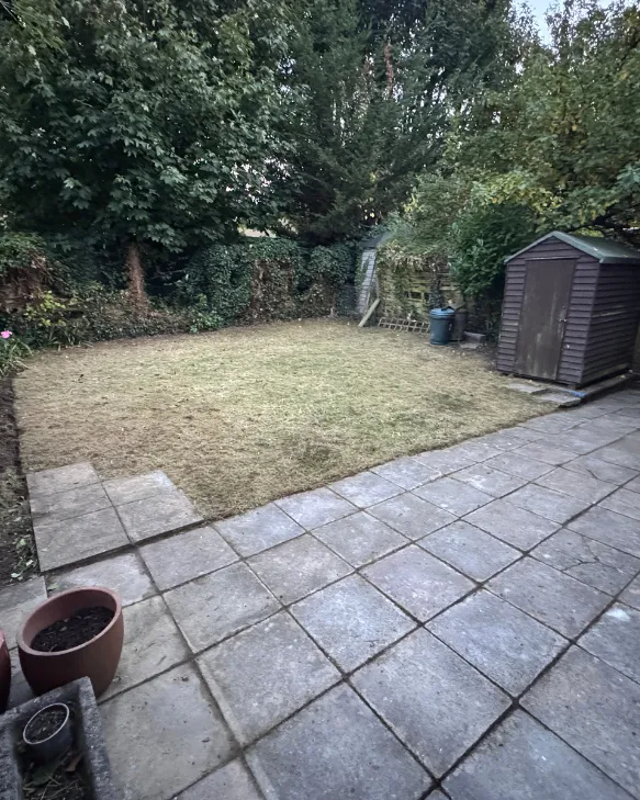 Mown lawn and swept patio beside a garden shed